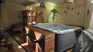 A spa area with a hot tub, wooden benches, a ladder, and a large window. - house for rent. (Caumont-sur-Durance)