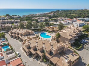 A resort with a central swimming pool surrounded by multi-story buildings with terracotta roofs.