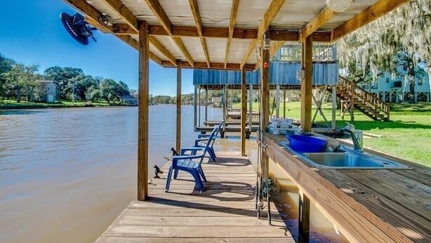 A wooden dock with chairs and a sink, overlooking a calm body of water.