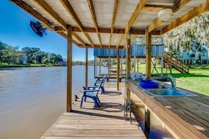 Een houten steiger met stoelen en een spoelbak, met uitzicht op een kalm waterlichaam.