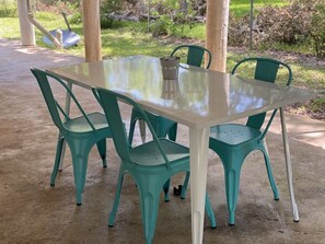 Une table avec quatre chaises, un pichet en métal et un sol en béton.
