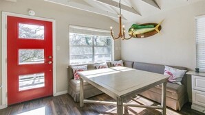 A room with a red door, a bench, a table, and a chandelier.