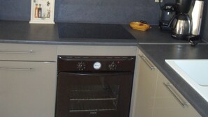 Una cocina con estufa, horno y cafetera.