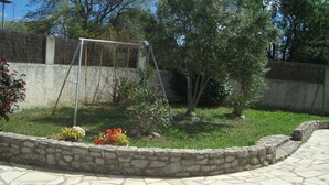 Un patio de piedra con un columpio y un pequeño árbol.