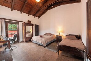 A bedroom with a bed, a desk, a chair, and a mirror.