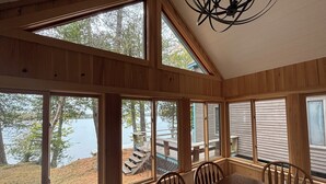 Ein Holzinterieur mit großen Fenstern, einem Esstisch und Stühlen.