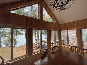 Un intérieur en bois, avec de grandes fenêtres, une table à manger et des chaises.