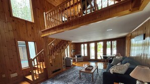 Ein geräumiger Wohnbereich mit einer Holztreppe, einem Sofa, einem Couchtisch und einem Esstisch.