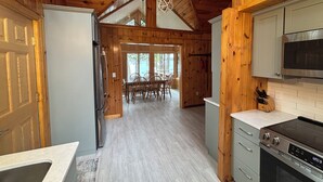 Ein Holzblockhaus Innenansicht mit Küche, Essbereich und einem großen Fenster.