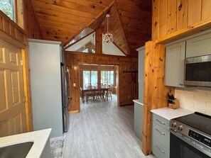 L’intérieur d’un chalet en bois comprend une cuisine, un coin repas et une grande fenêtre.