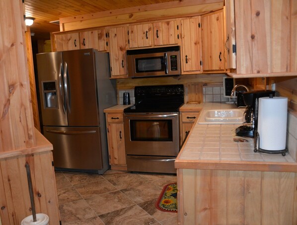 Una cocina con armarios de madera, electrodomésticos de acero inoxidable, microondas, horno y un lavabo.