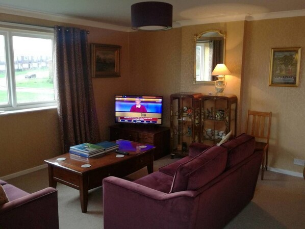 A living room with a television, a sofa, a coffee table, and a cabinet.