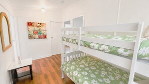 A room with bunk beds, a small table, and a wall with a decorative number art piece. - Teke Cottage - traditional fishermans cottage (Wooli)