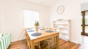 A dining area with a wooden table, six chairs, and a vase with flowers.