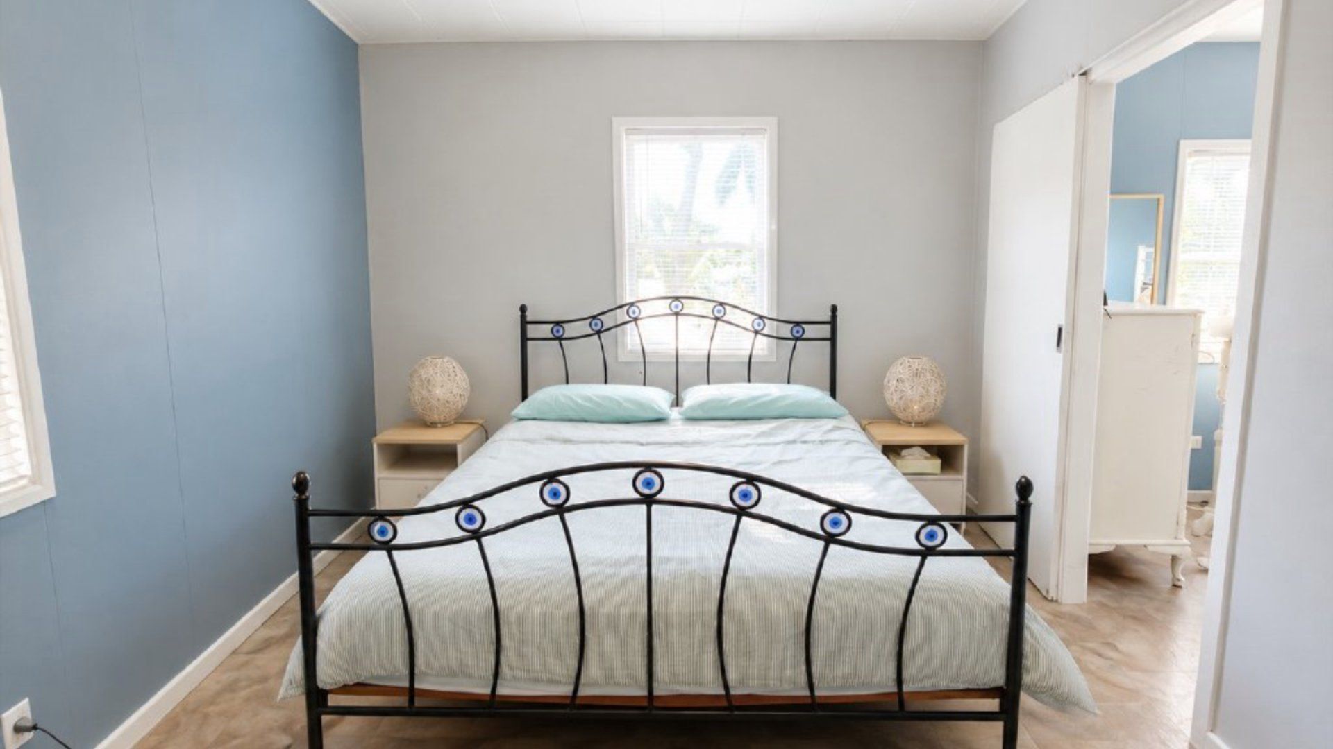Una camera da letto con una struttura letto in metallo, due comodini e una finestra.