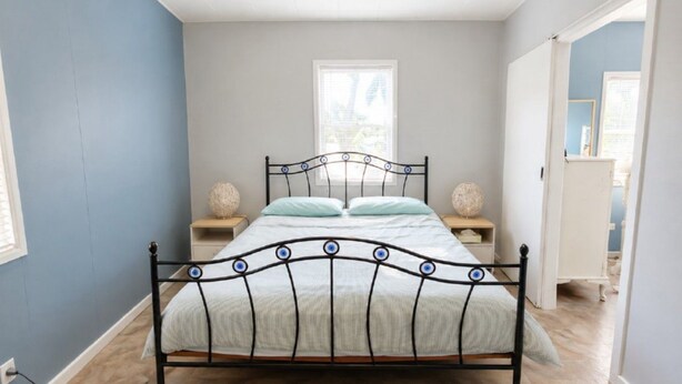 A bedroom with a metal bed frame, two bedside tables, and a window.