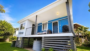 A two-story house with a balcony, a covered outdoor seating area, and a fenced yard.