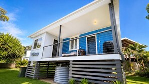 A two-story house with a balcony, a covered outdoor seating area, and a fenced yard.