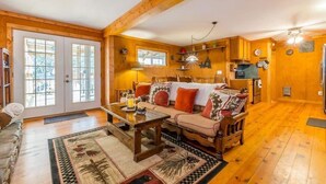 A cozy wooden interior with a sofa, a coffee table, and a dining area.