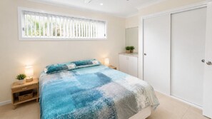 A bedroom with a bed, bedside tables, a wardrobe, and a window with blinds. - Sandy Feet - Perfect Getaway (WOOLI)