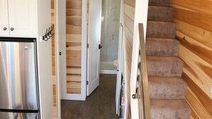 Une cuisine moderne avec un réfrigérateur en acier inoxydable, des murs en bois et un escalier menant à une mezzanine.