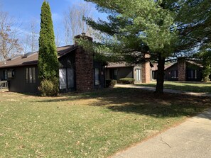 A residential area with houses featuring brick and siding exteriors, surrounded by trees and a grassy lawn. - The Pines of Apple Valley. 31 Beautiful Vacation Cabins. (Howard)