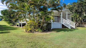 A house with a white exterior, a covered porch, and a staircase leading to a deck.