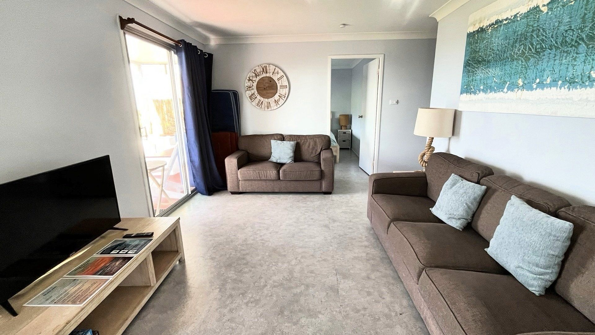 A living room with a sofa, a TV stand, and a painting on the wall.