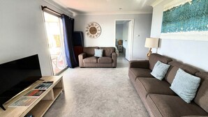 Ein Wohnzimmer mit Sofa, TV-Schrank und einem Bild an der Wand.