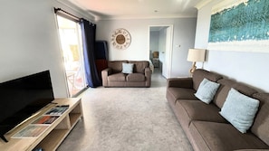 Ein Wohnzimmer mit Sofa, TV-Schrank und einem Bild an der Wand.