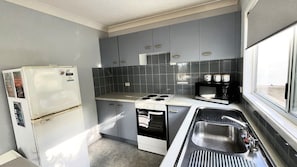 Eine kleine Küche mit Kühlschrank, Herd, Mikrowelle und Spüle.