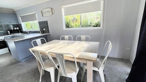 A compact kitchen with a dining area, a microwave, a coffee maker, and a window with a view of greenery.