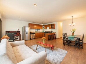 A modern apartment with a living room, dining area, and kitchen.
