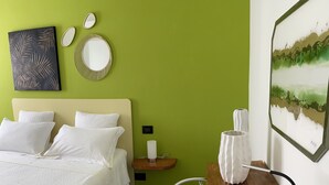 A hotel room with a bed, a nightstand, a chair, a desk, and a wall with artwork. - Entire apartment on the first floor (Piumazzo)
