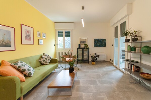 A living room with a green sofa, a wooden coffee table, and a bookshelf with decorative items.