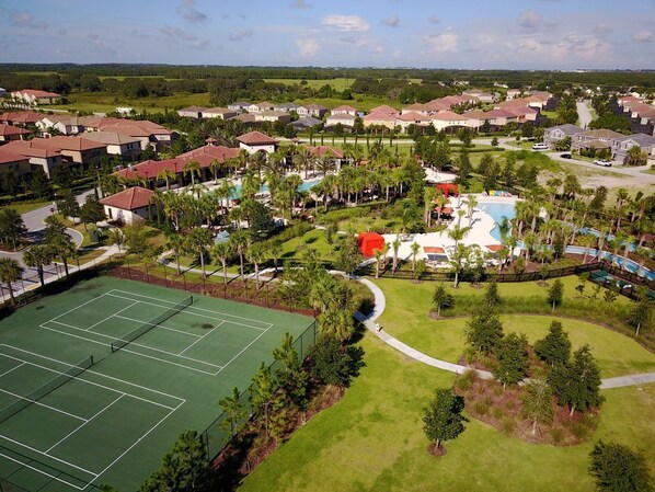 Zona residencial con cancha de tenis, piscina y varias casas.