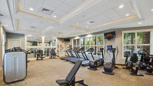 Une salle de sport équipée de tapis de course, de vélos elliptiques et de matériel de musculation.
