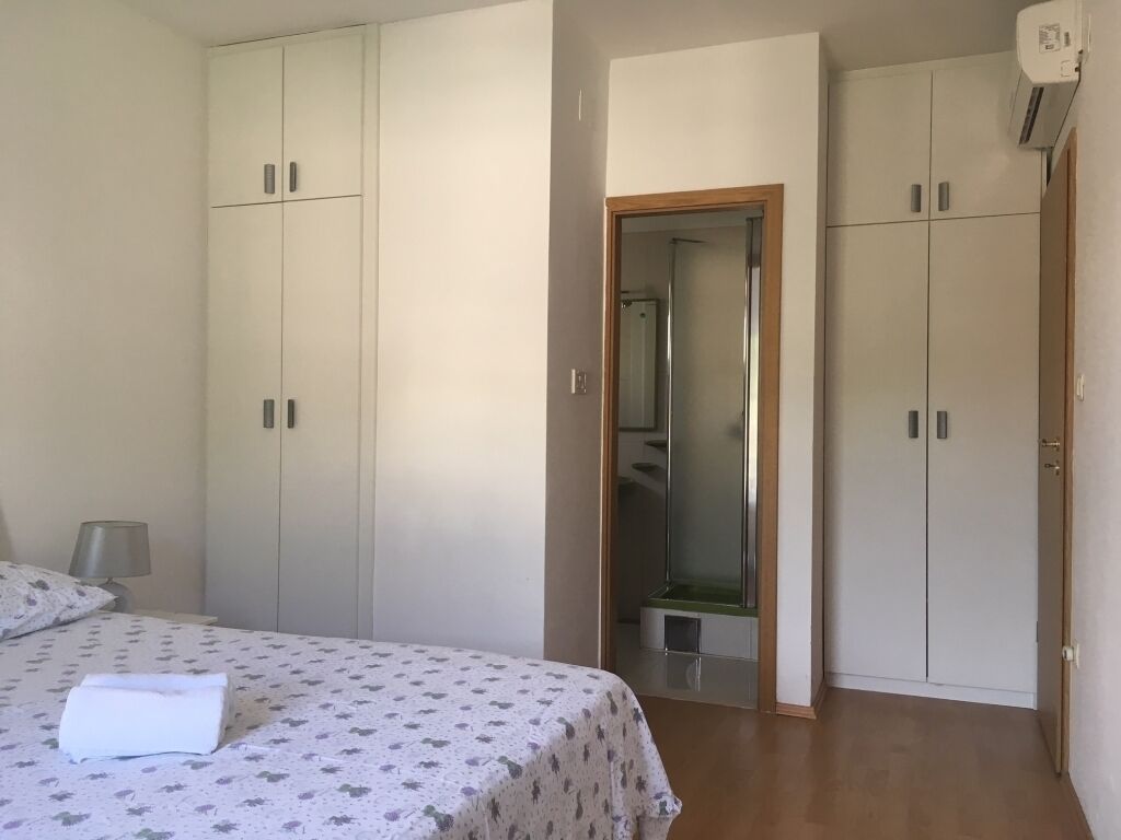 A bedroom with a bed, a wardrobe, and a mirror.