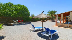 An outdoor seating area with two blue lounge chairs and a thatched umbrella. - Alcoraia 408 traditional finca with private pool, terrace, barbecue and air conditioning (Campos)