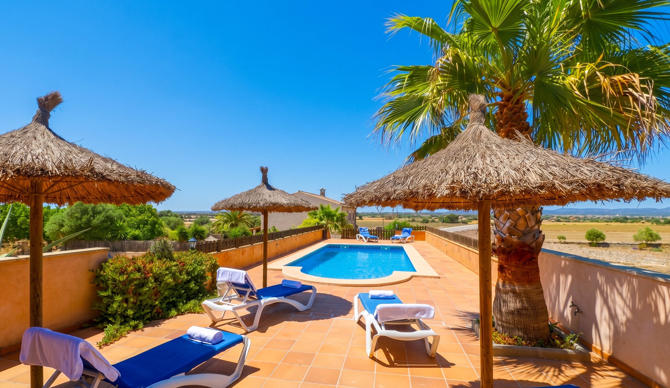 A poolside area with lounge chairs, a swimming pool, and thatched umbrellas.