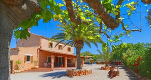 Un edificio de dos pisos con un patio, asientos al aire libre y una palmera.