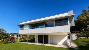 A modern two-story building with a flat roof, large windows, and a sloped glass facade.