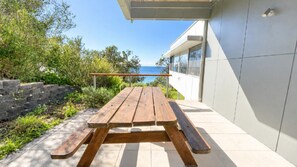 A wooden picnic table with a view of the sea.