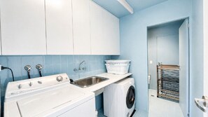 A laundry area with a washing machine, a dryer, a sink, and a laundry basket.