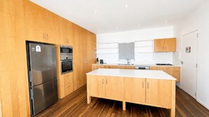 A modern kitchen with wooden cabinets, stainless steel appliances, and a large island.