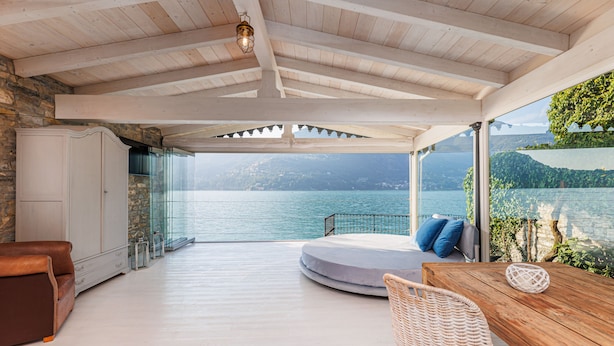 A spacious room with a wooden ceiling, a view of the sea, a round seating area, and a dining table with chairs. - The dock of Villa Sardagna (blevio)
