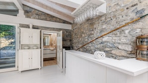 A kitchen with white cabinetry, a stone wall, and a wooden ceiling. - The dock of Villa Sardagna (blevio)
