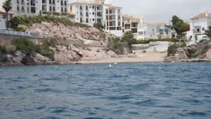 A coastal area with buildings along the shore, a rocky cliff, and a beach. - APTO, WIFI in ACANTILADO 'VIEW TO THE SEA'. PARKING (Aguilas)