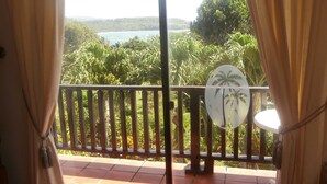A balcony with a view of a lush landscape and a body of water. - Casa Clara | 6BR Villa with Pool & Ocean View | Sleeps 12, Bacolet Tobago (Tobago)