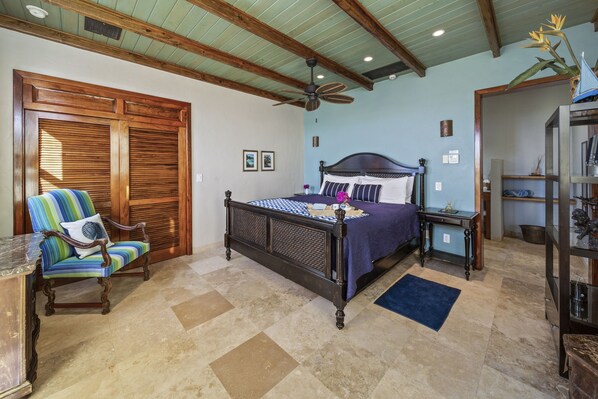 A bedroom with a large bed, a chair, a nightstand, and a bookshelf.